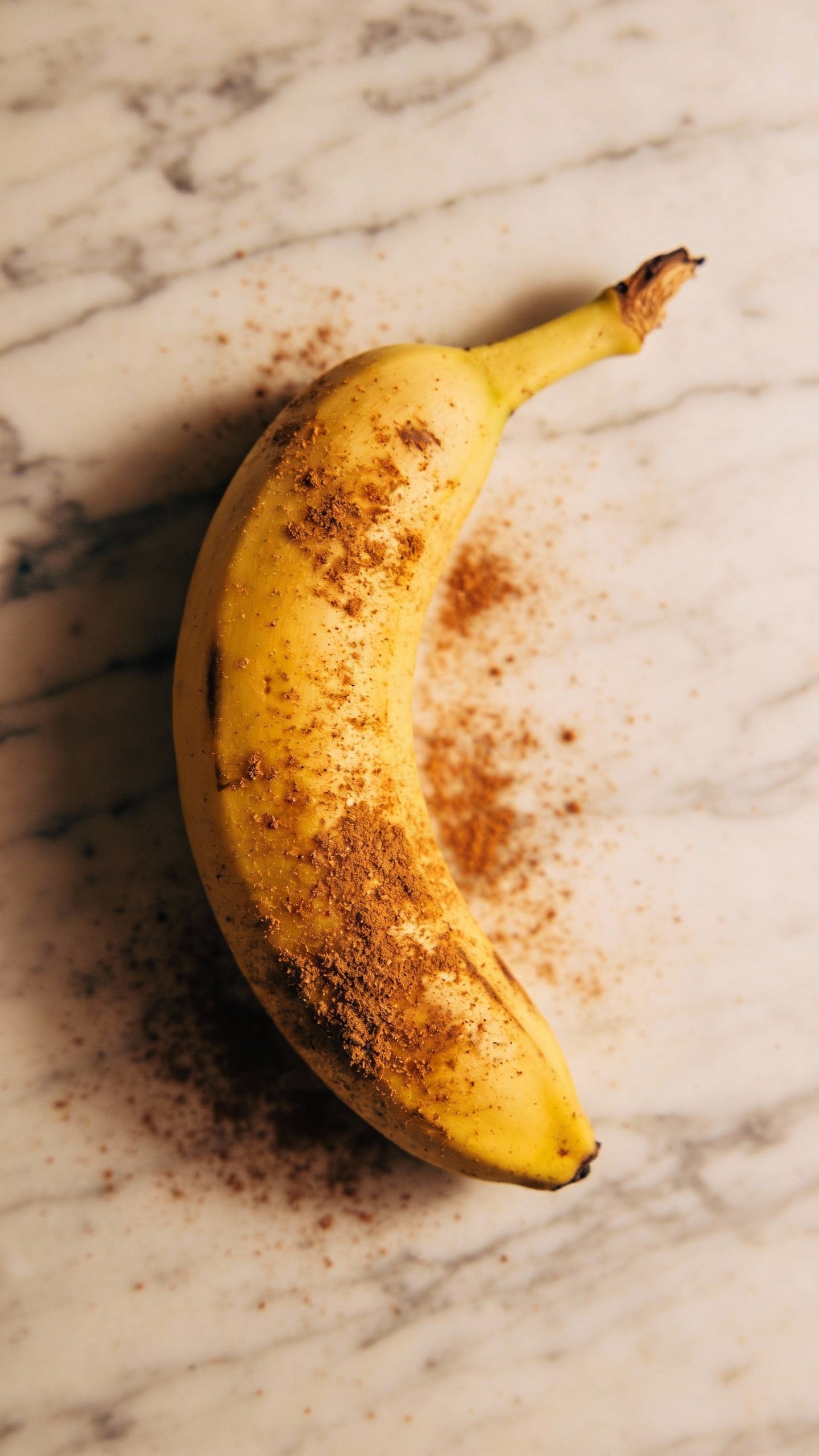 single ripe banana dusted with cinnamon on marble surface