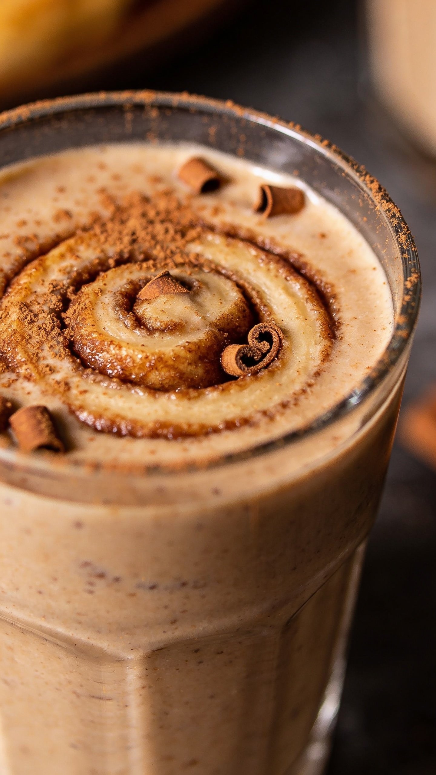 closeup cinnamon roll protein smoothie in clear glass, cinnamon dusted