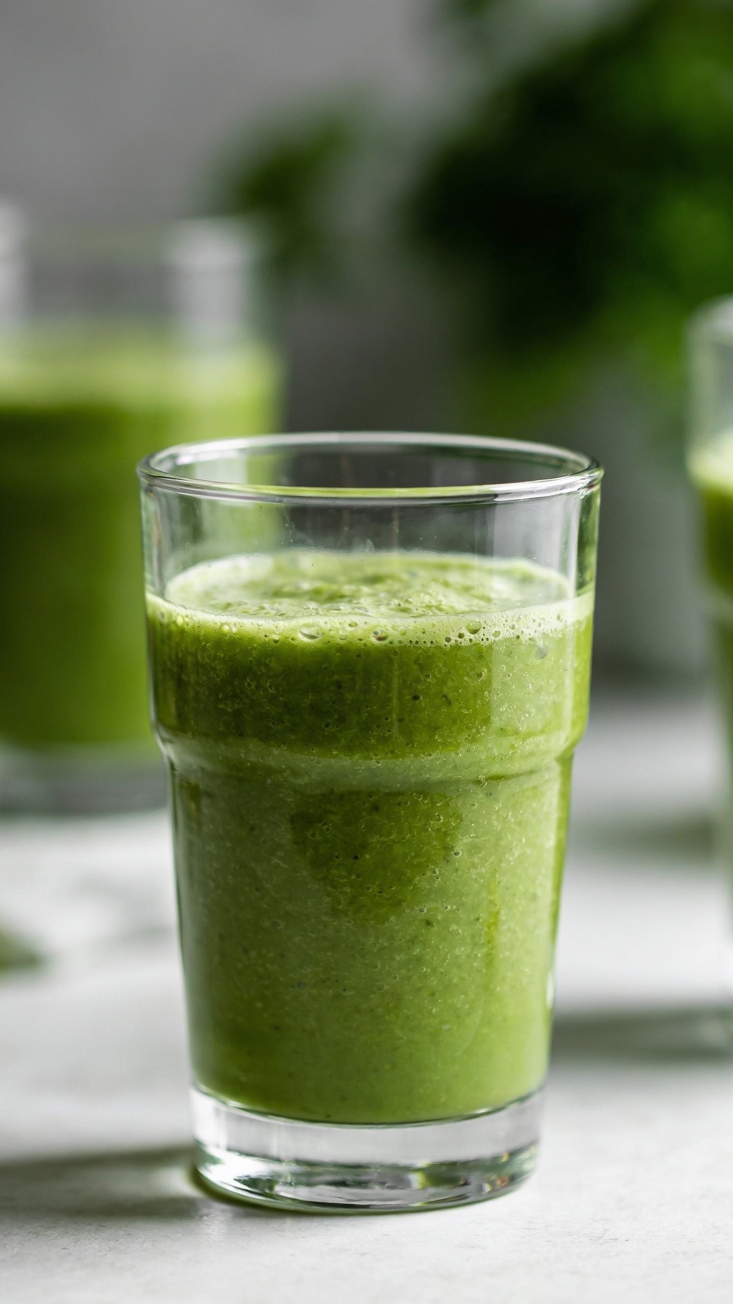 closeup of green protein smoothie in clear glass, natural light