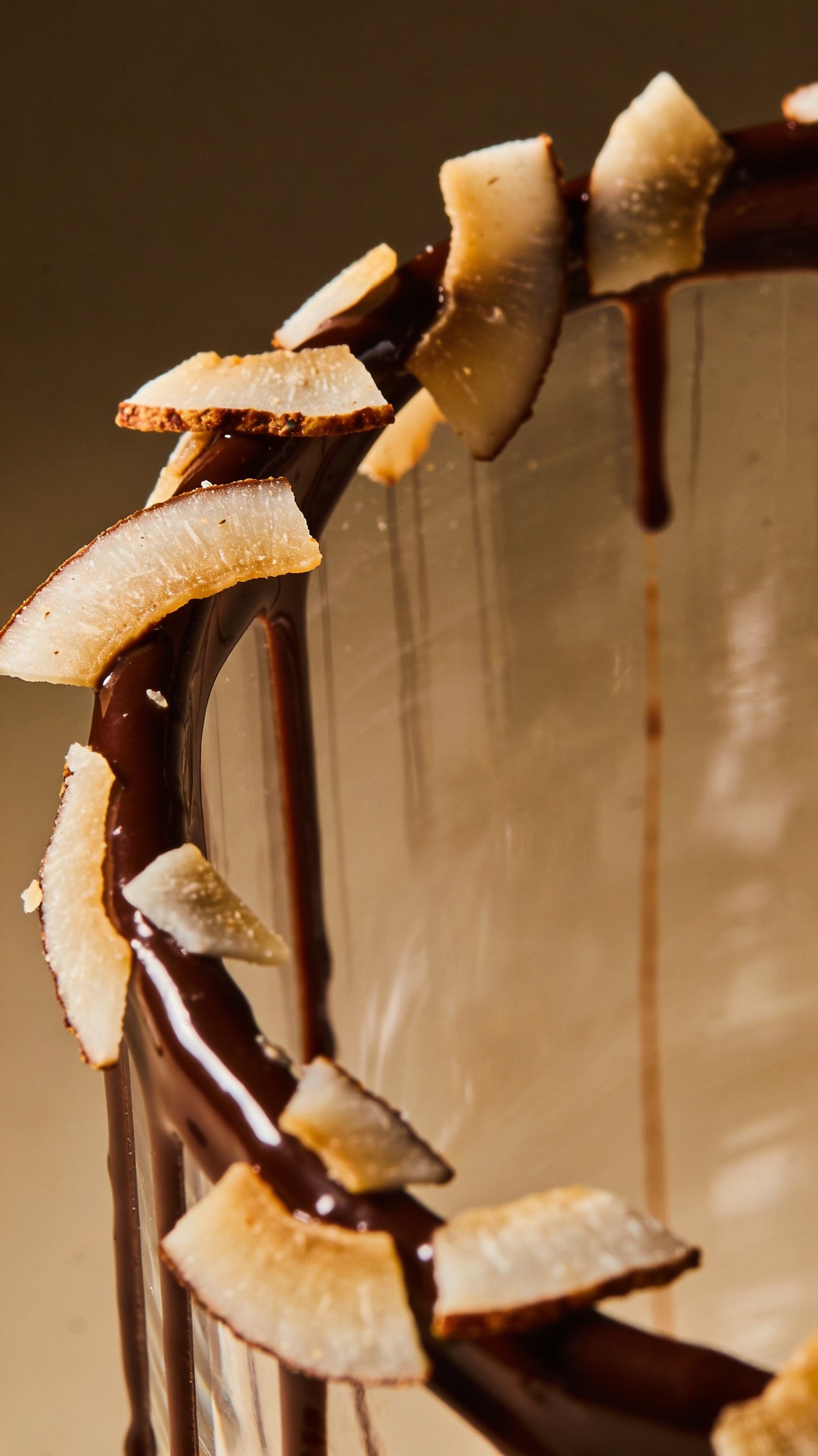 macro of toasted coconut flakes on chocolate-drizzled rim glass