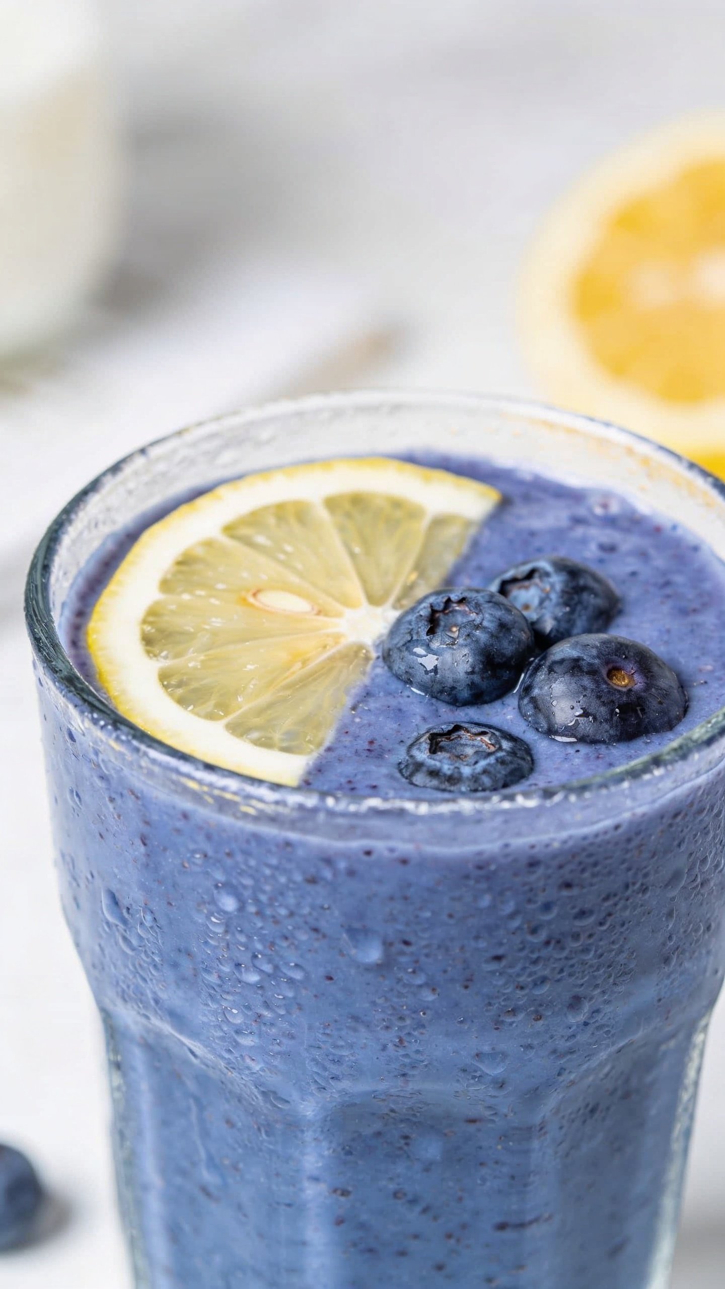 closeup blueberry lemon smoothie in clear glass, condensation, daylight