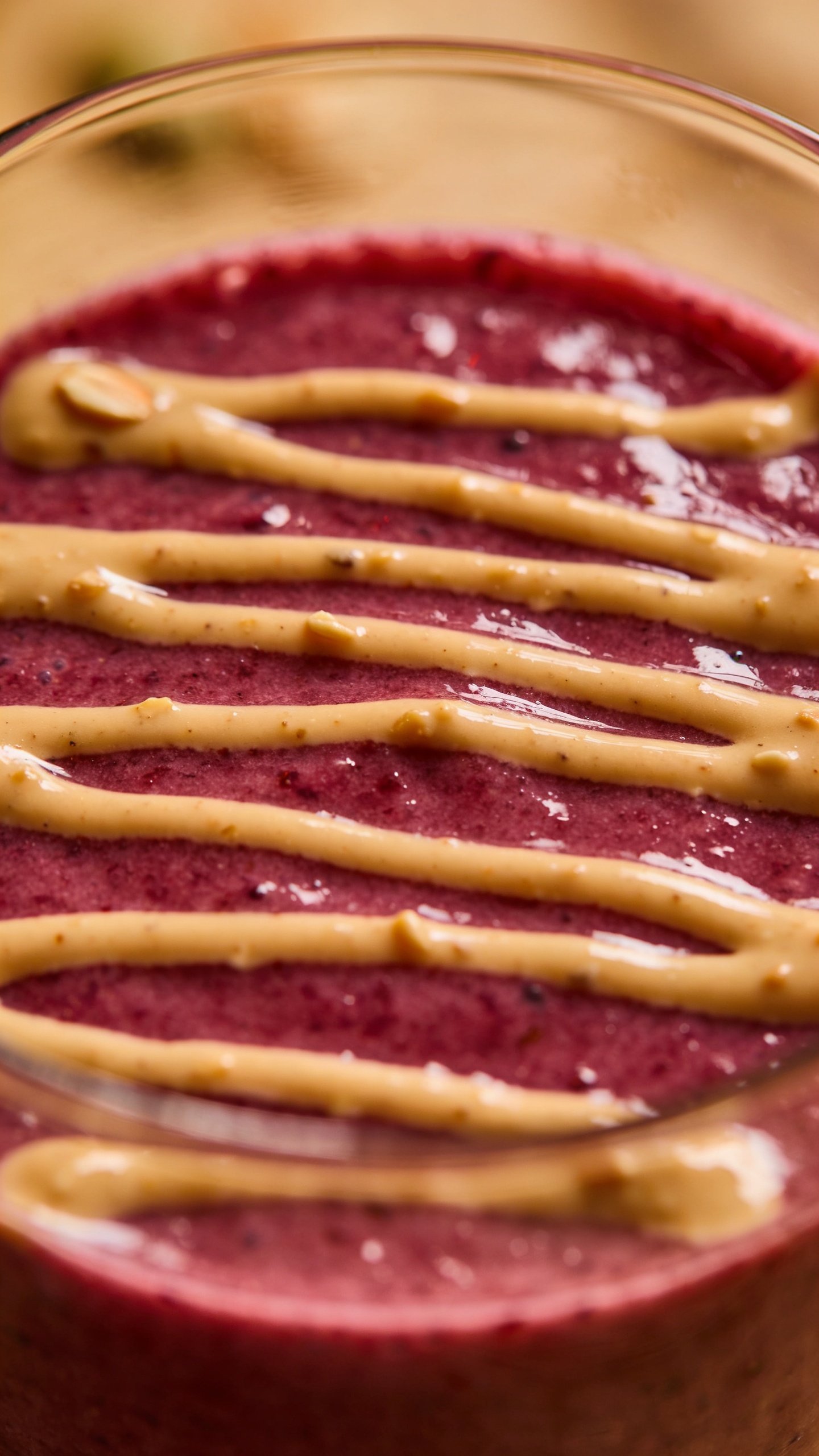 drizzle of almond butter atop berry smoothie, macro shot