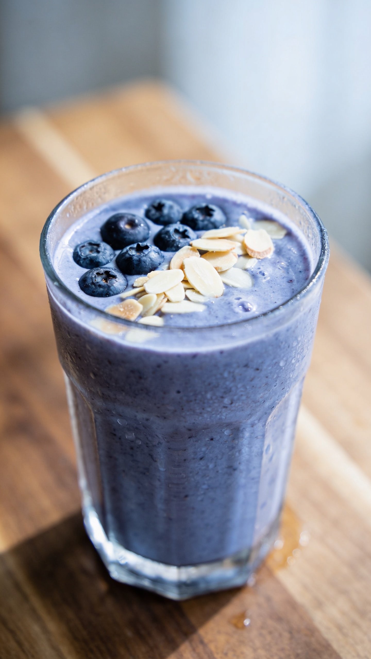 closeup blueberry almond smoothie in clear glass, soft morning light