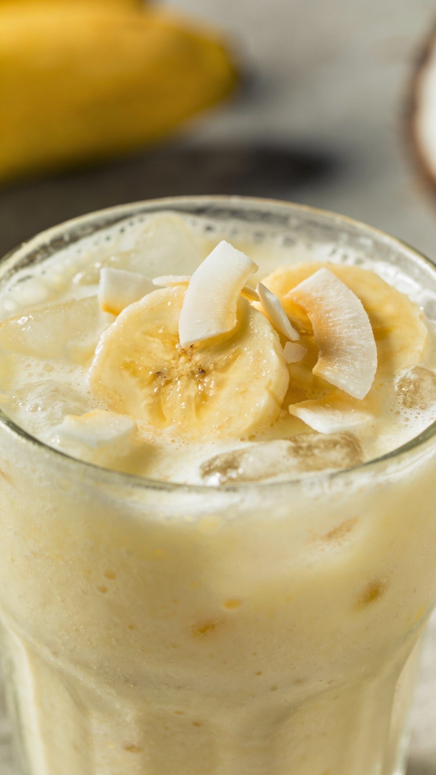 frosty banana coconut smoothie in clear glass, closeup