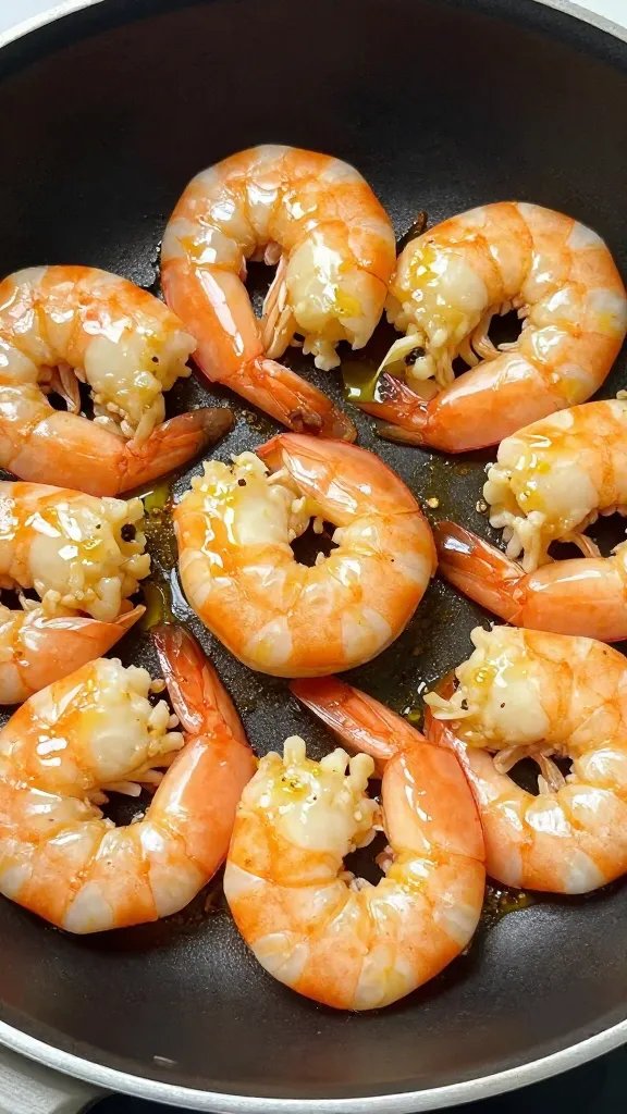 Closeup skillet of garlic butter shrimp, glossy lemon glaze