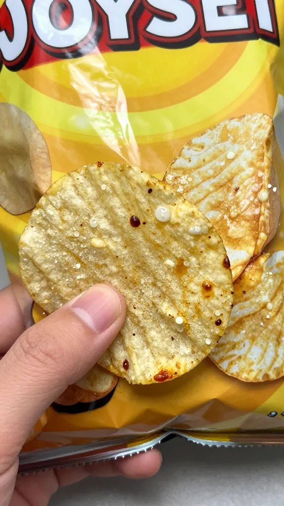 closeup of greasy potato chip bag gripped by one hand