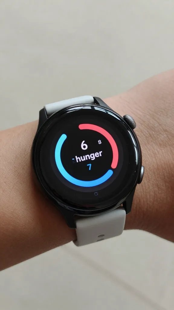 smartwatch showing 6–7 hunger scale on wrist, soft light