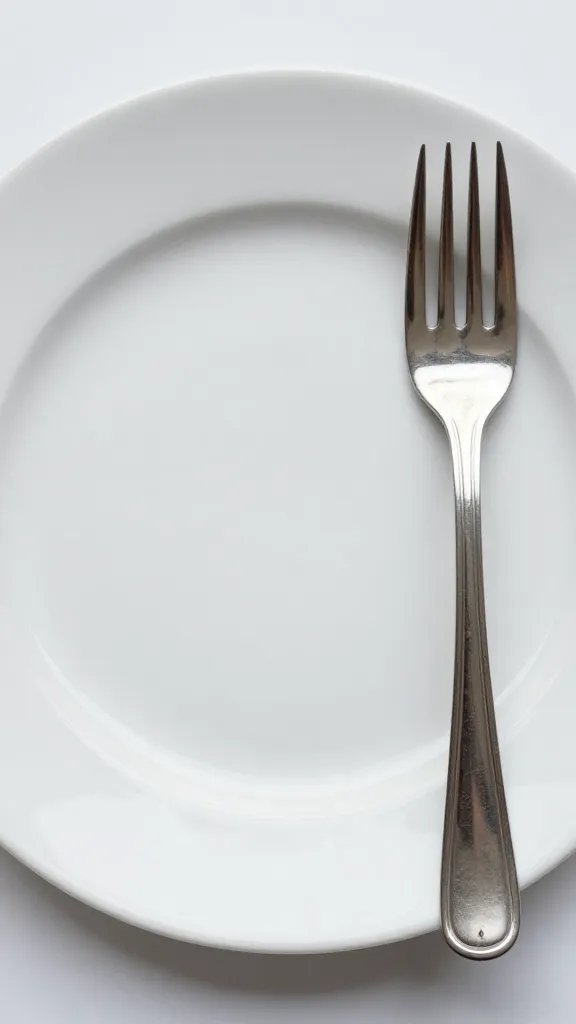 empty white dinner plate with silver fork, tight top-down shot